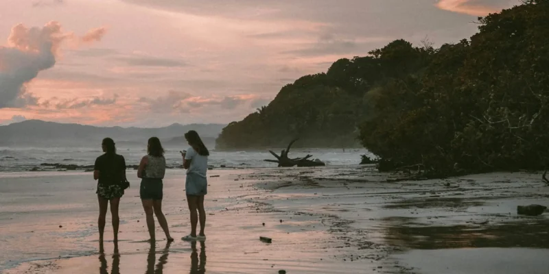 Drie mensen op het strand bij zonsondergang in Costa Rica duiken met haaien