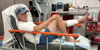 John Schweizer zit na de haaienbeet op de Bahama's op een ziekenhuisbed met zijn linkeronderbeen in het verband