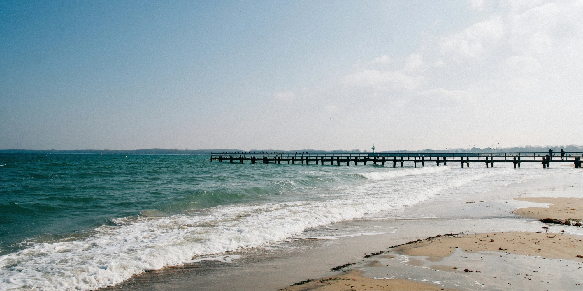 Houten steiger aan het Oostzeestrand met Travemünde op de achtergrond