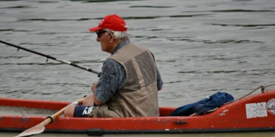 Man met een hengel in een rode kajak op het water