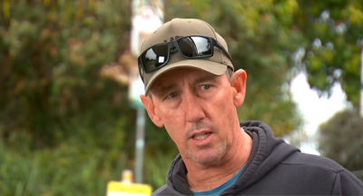 Surfer Matthew Devine met een pet en een zonnebril op de klep tijdens een interview