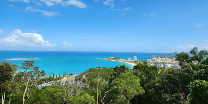 Uitzicht vanaf een beboste heuvel over de turquoise baai en de stad Nouméa
